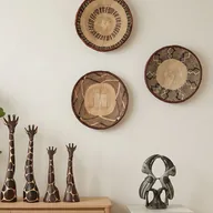 Handwoven Binga wall baskets above carved wooden giraffes and a stone sculpture